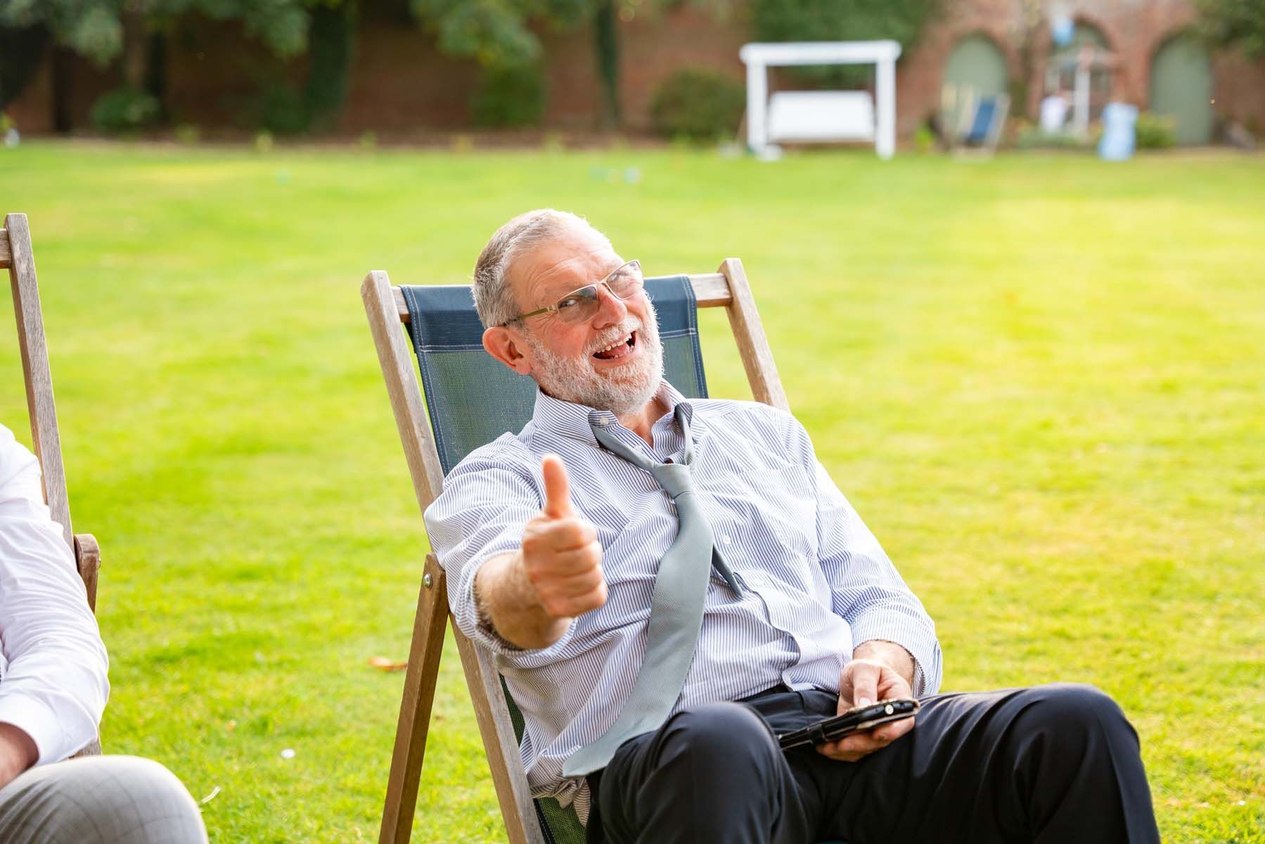 A man is sitting in a lawn chair giving a thumbs up.