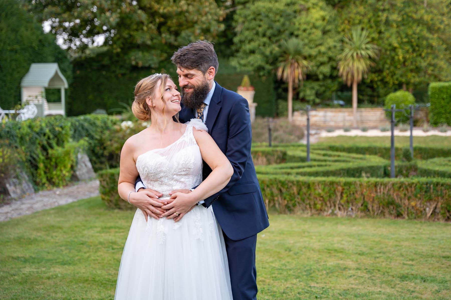 A bride and groom are posing for a picture in a garden.