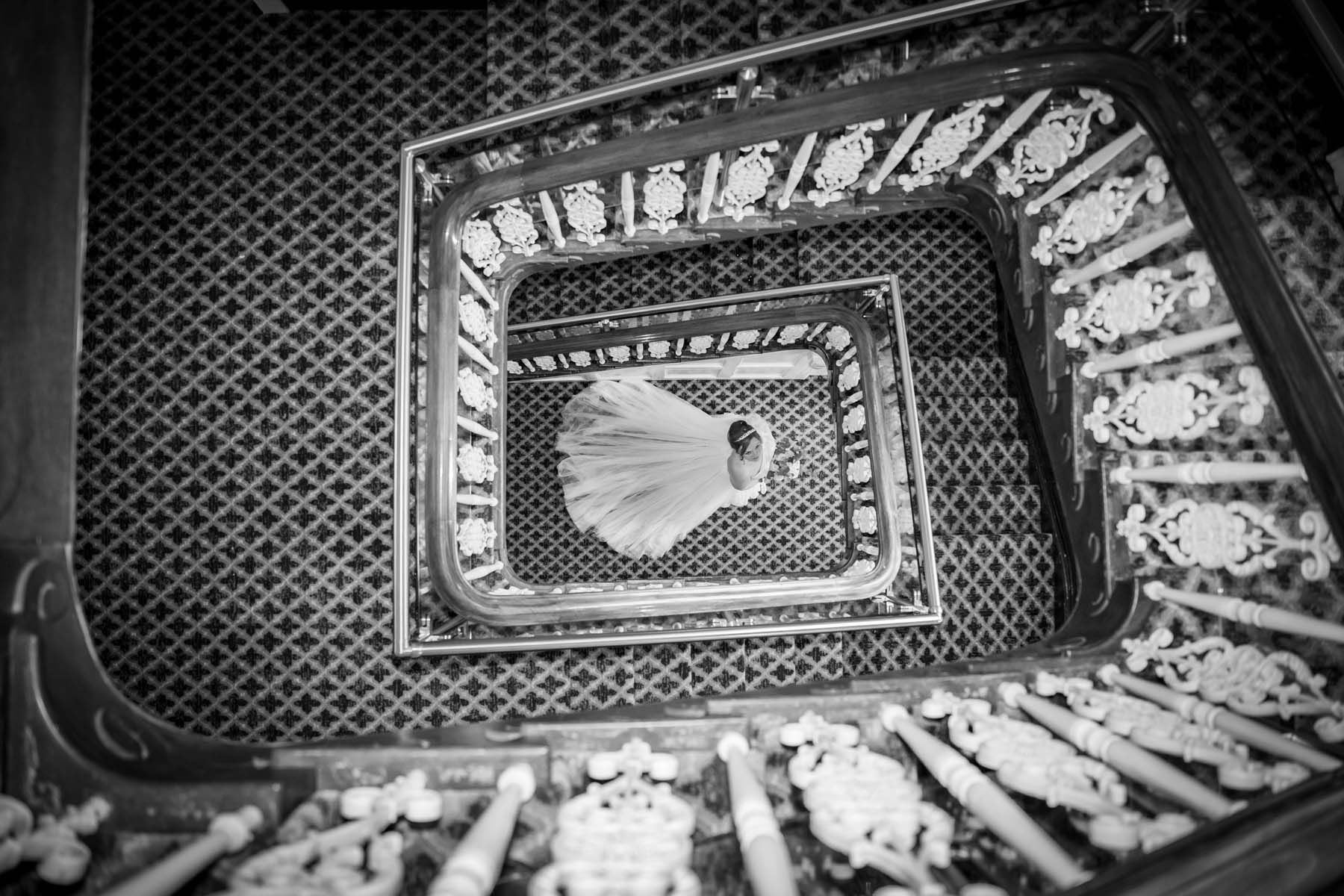 A black and white photo of a spiral staircase with a bride in the middle.