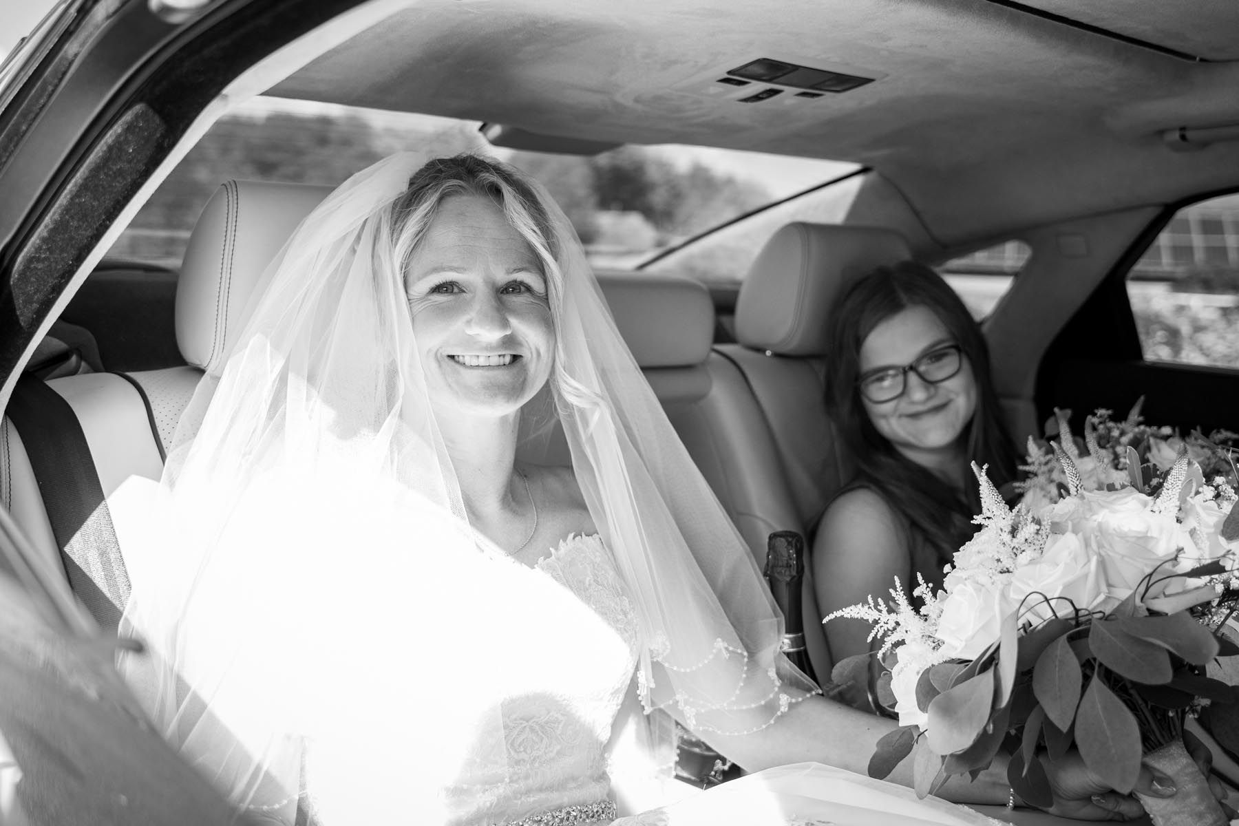 A bride and her daughter are sitting in the back seat of a car.