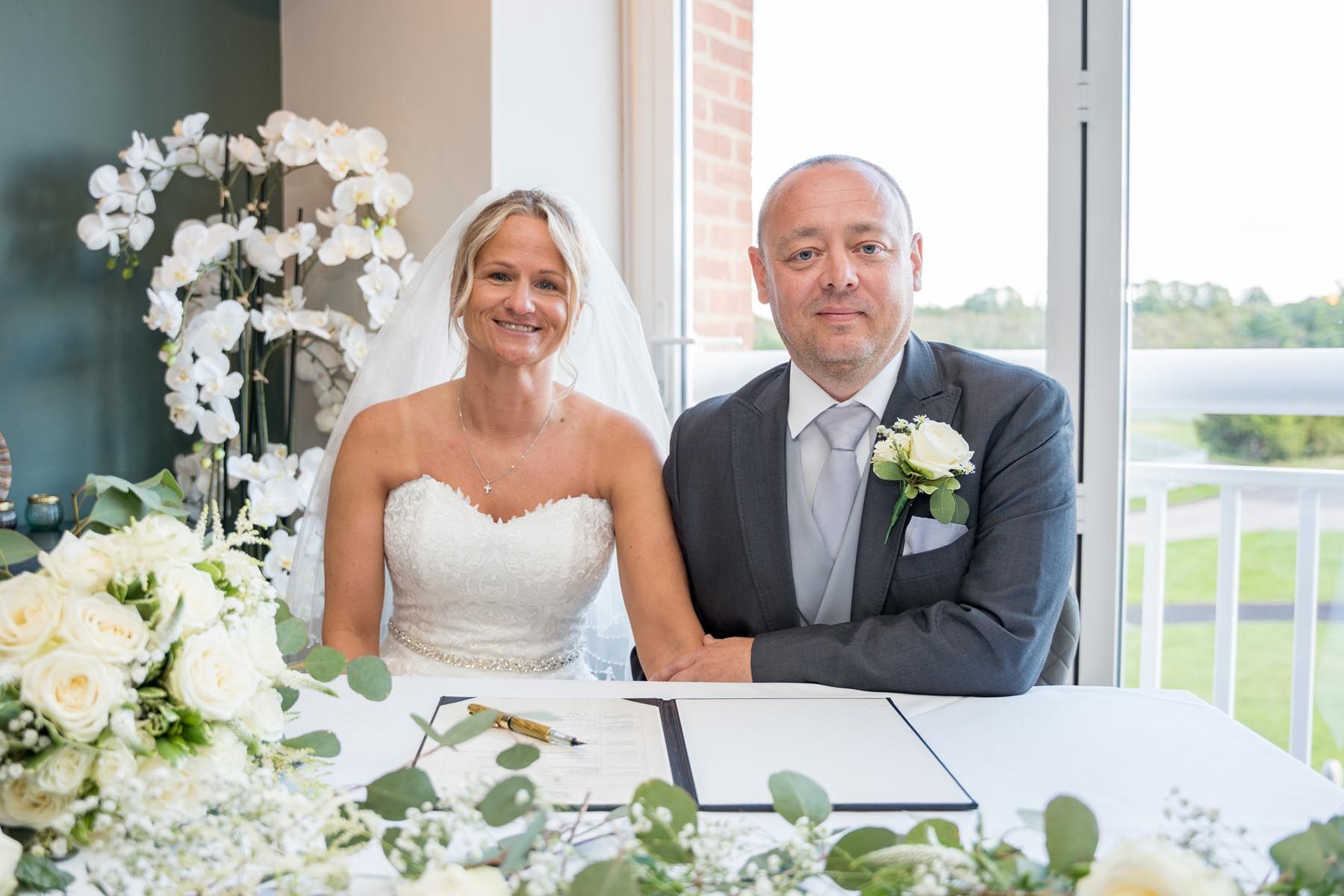 A bride and groom are sitting at a table with flowers.