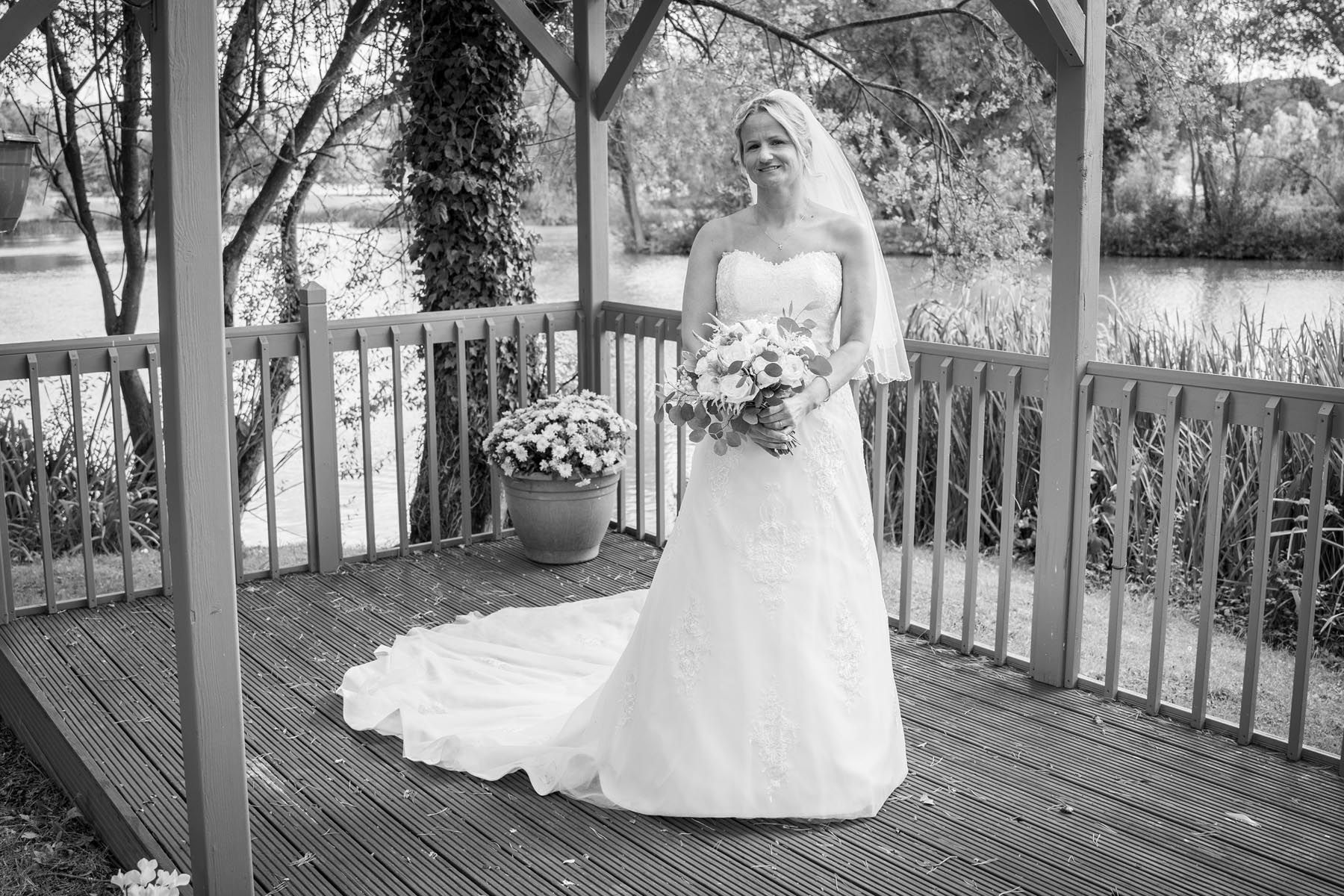 A bride in a wedding dress is standing on a deck holding a bouquet of flowers.