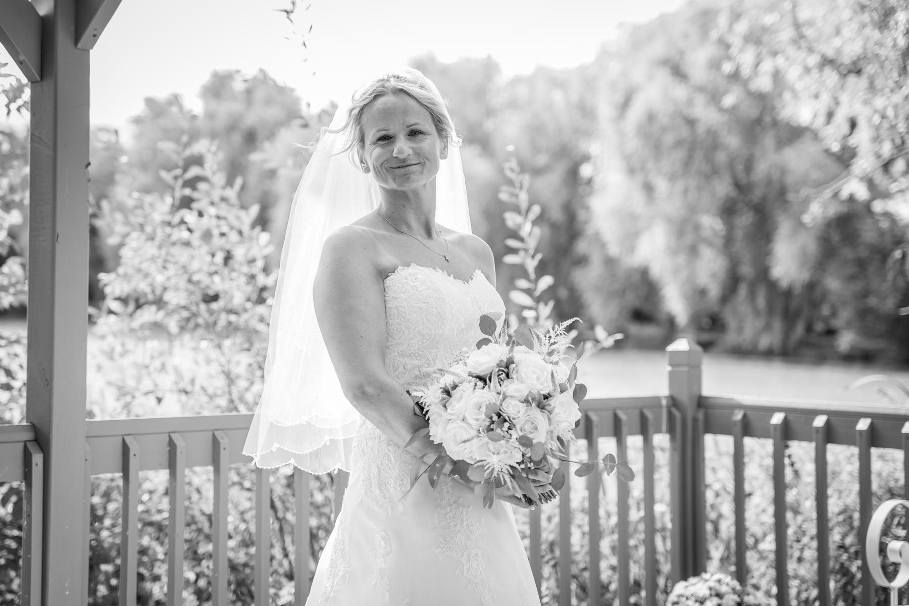 A black and white photo of a bride in a wedding dress holding a bouquet of flowers.