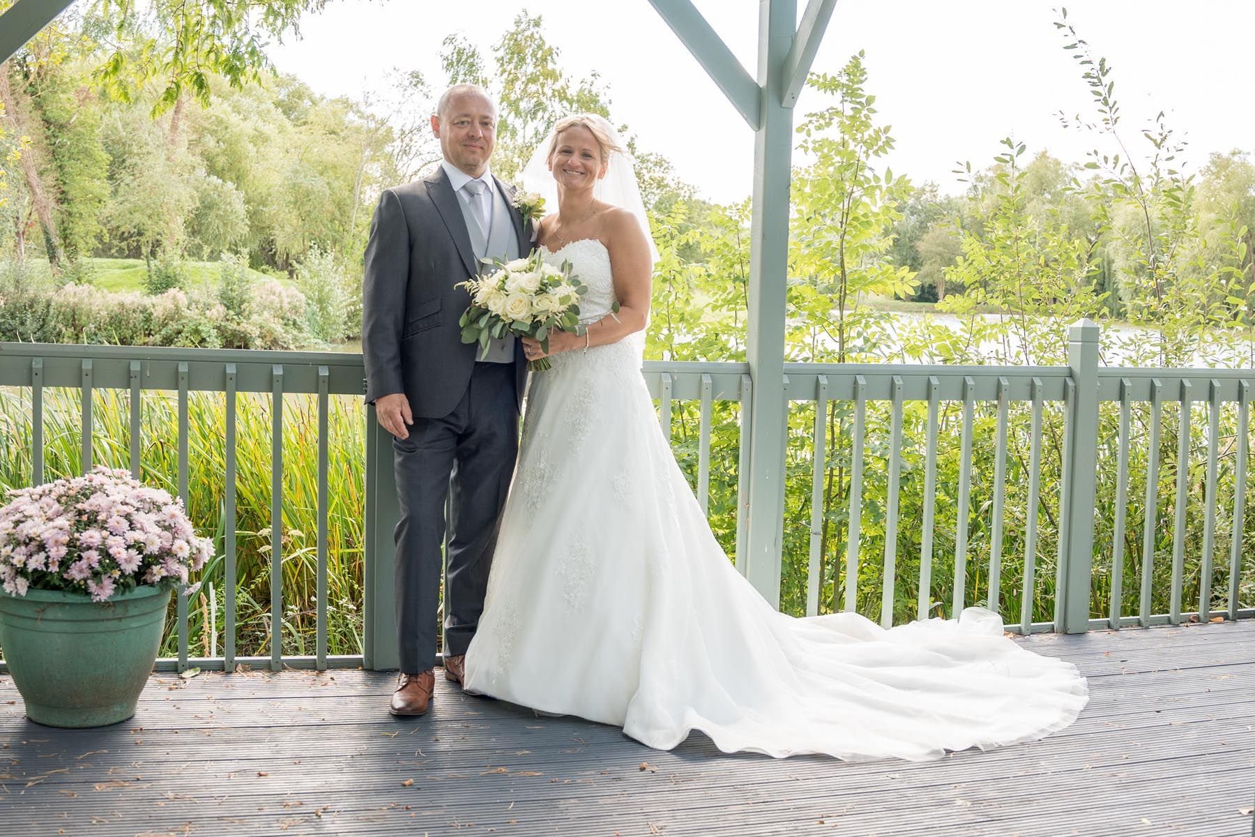 A bride and groom are posing for a picture on a balcony.