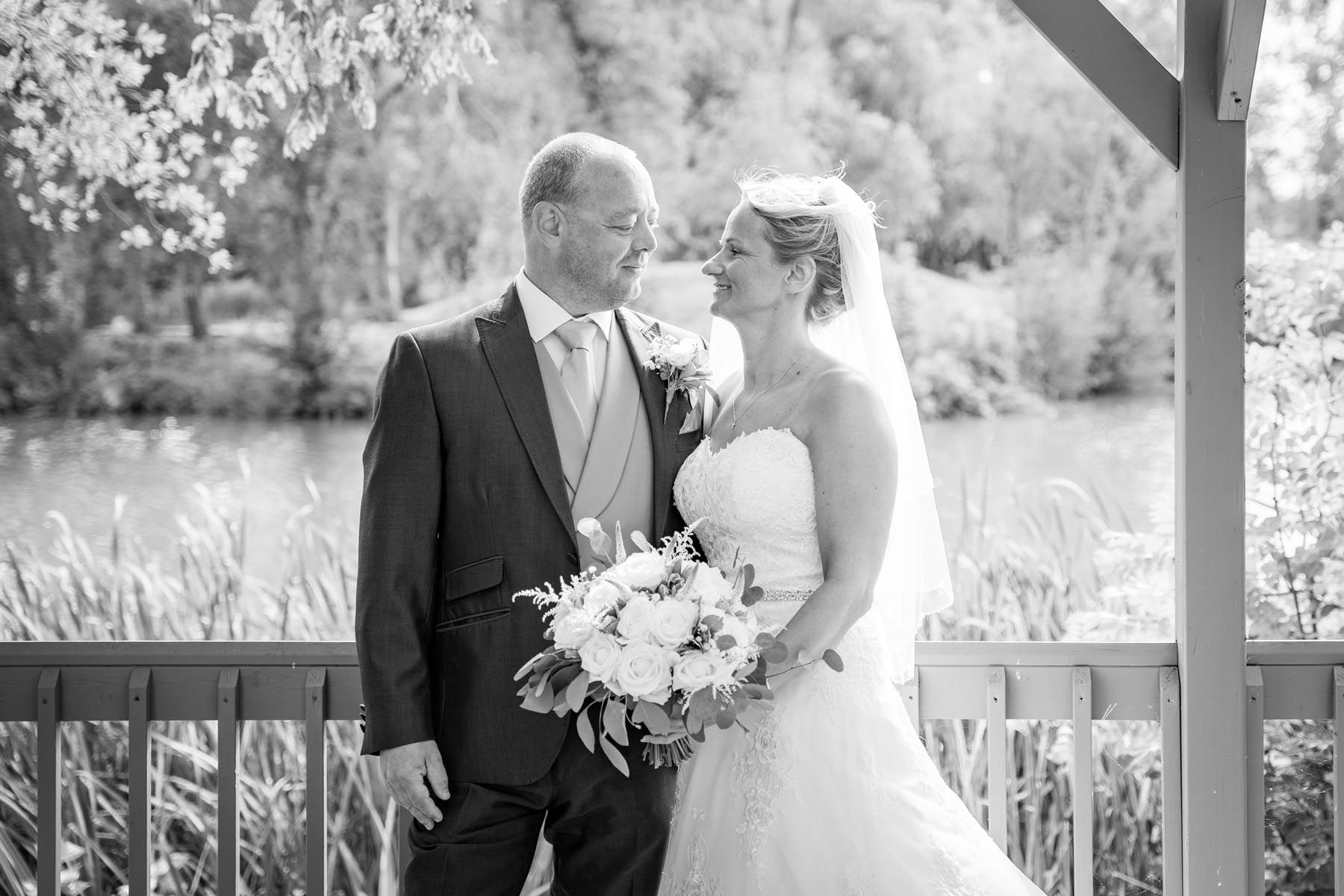 A black and white photo of a bride and groom standing next to each other on a balcony.