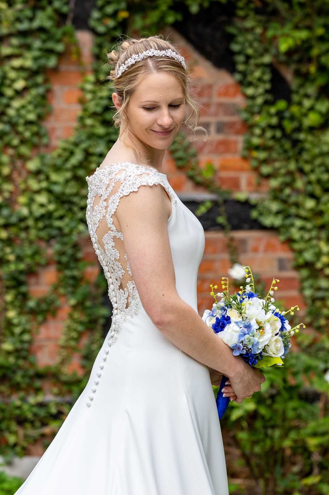 A bride in a white dress is holding a bouquet of blue and white flowers.