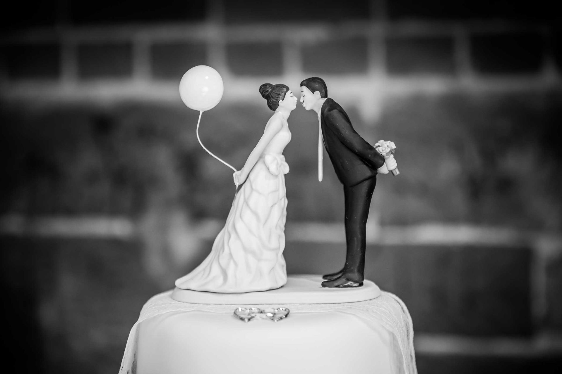A black and white photo of a bride and groom figurine on top of a wedding cake.