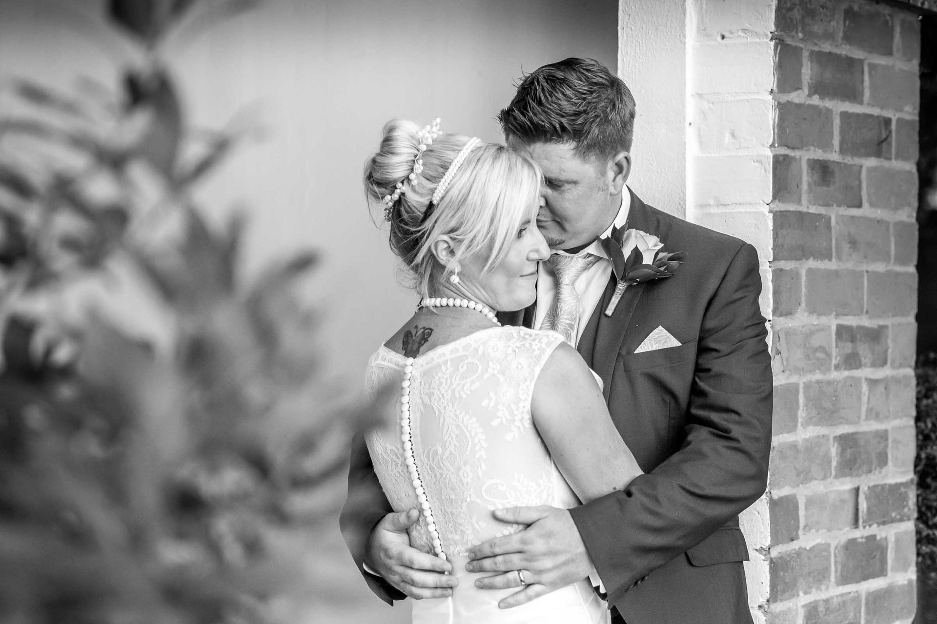 A black and white photo of a bride and groom hugging each other.