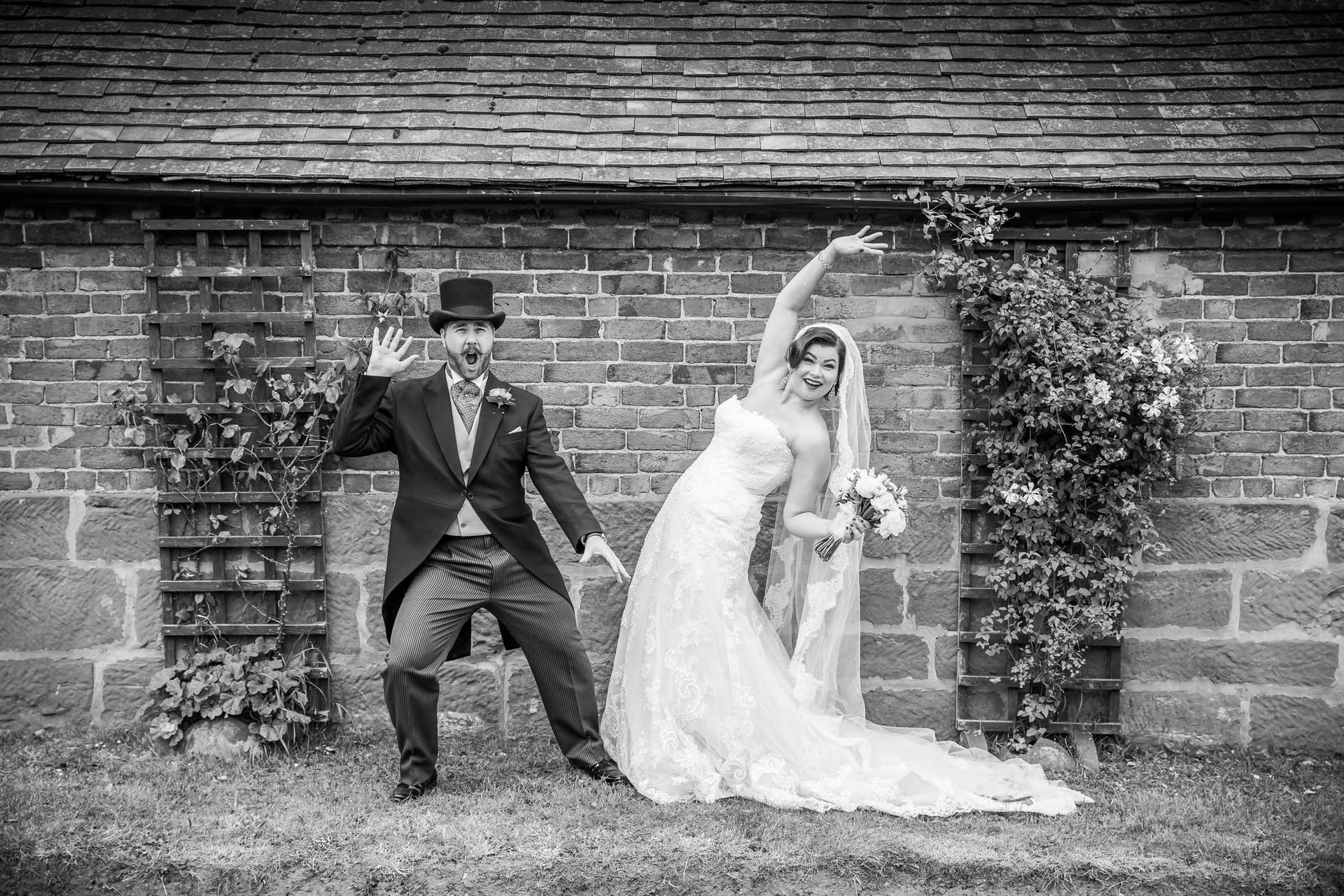 A bride and groom are posing for a picture in front of a brick wall.