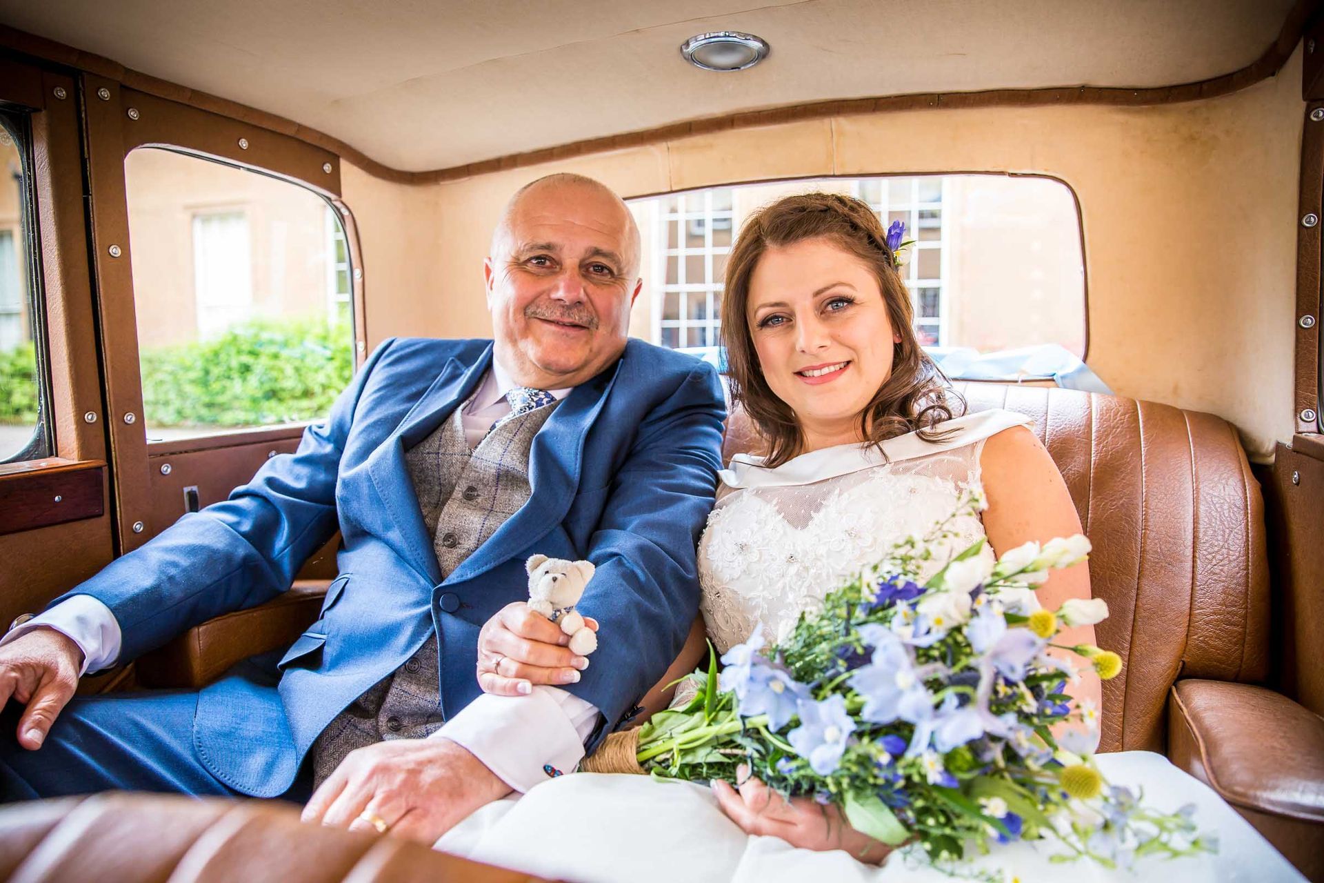 A bride and groom are sitting in the back seat of a car.