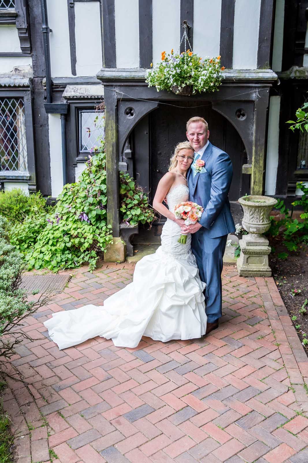 A bride and groom are posing for a picture in front of a building.