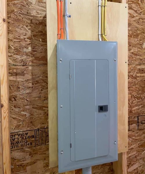 A gray electrical box is mounted on a wooden wall.
