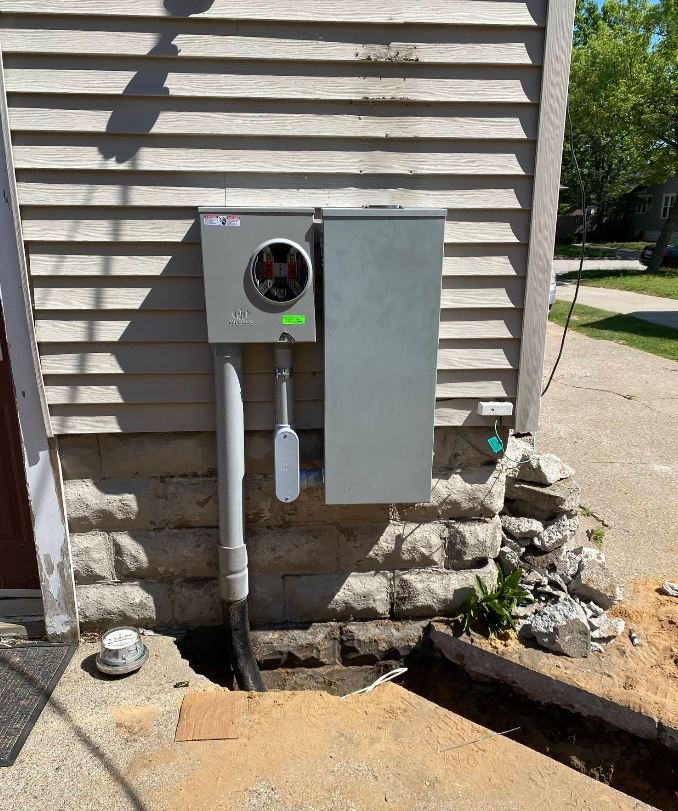 An electrical box is installed on the side of a house.
