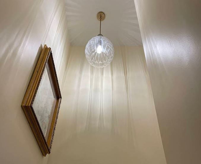 There is a picture on the wall and a light hanging from the ceiling.