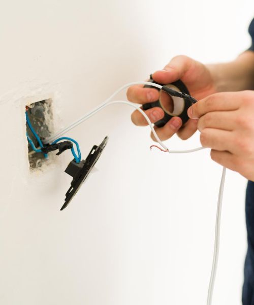 A person is fixing an electrical outlet with a pair of scissors