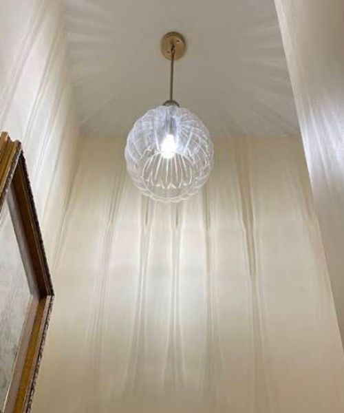 A light fixture is hanging from the ceiling in a hallway.