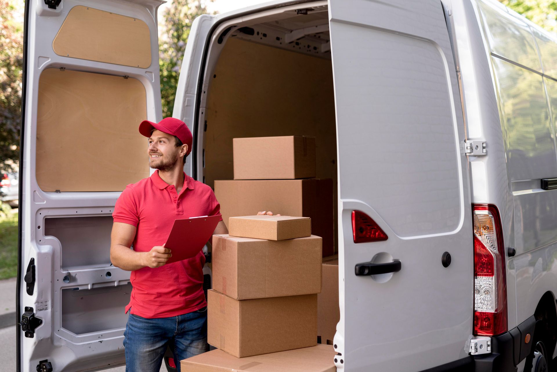 A delivery man is standing in front of a van filled with boxes.