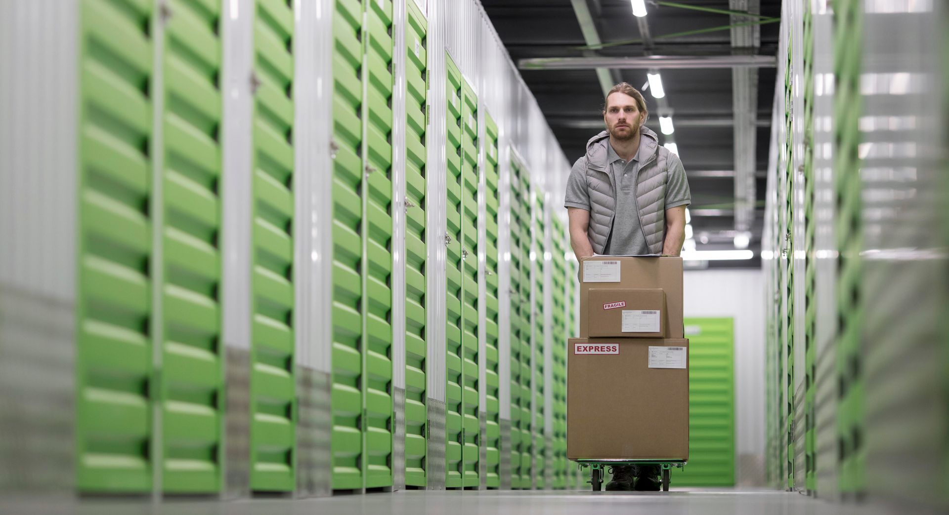 A man is pushing a cart with boxes in a warehouse.