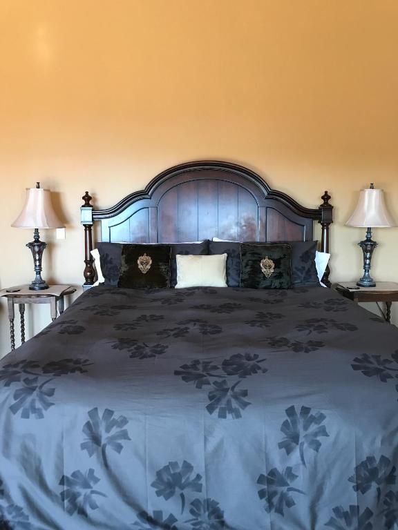 Bedroom with dark floral bedspread, ornate dark headboard, and two lamps on nightstands.