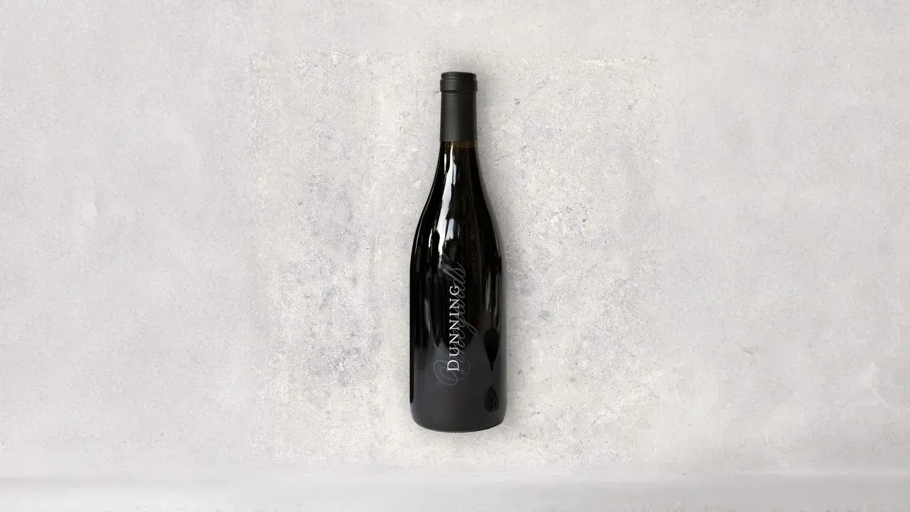 A bottle of wine is sitting on a white surface.