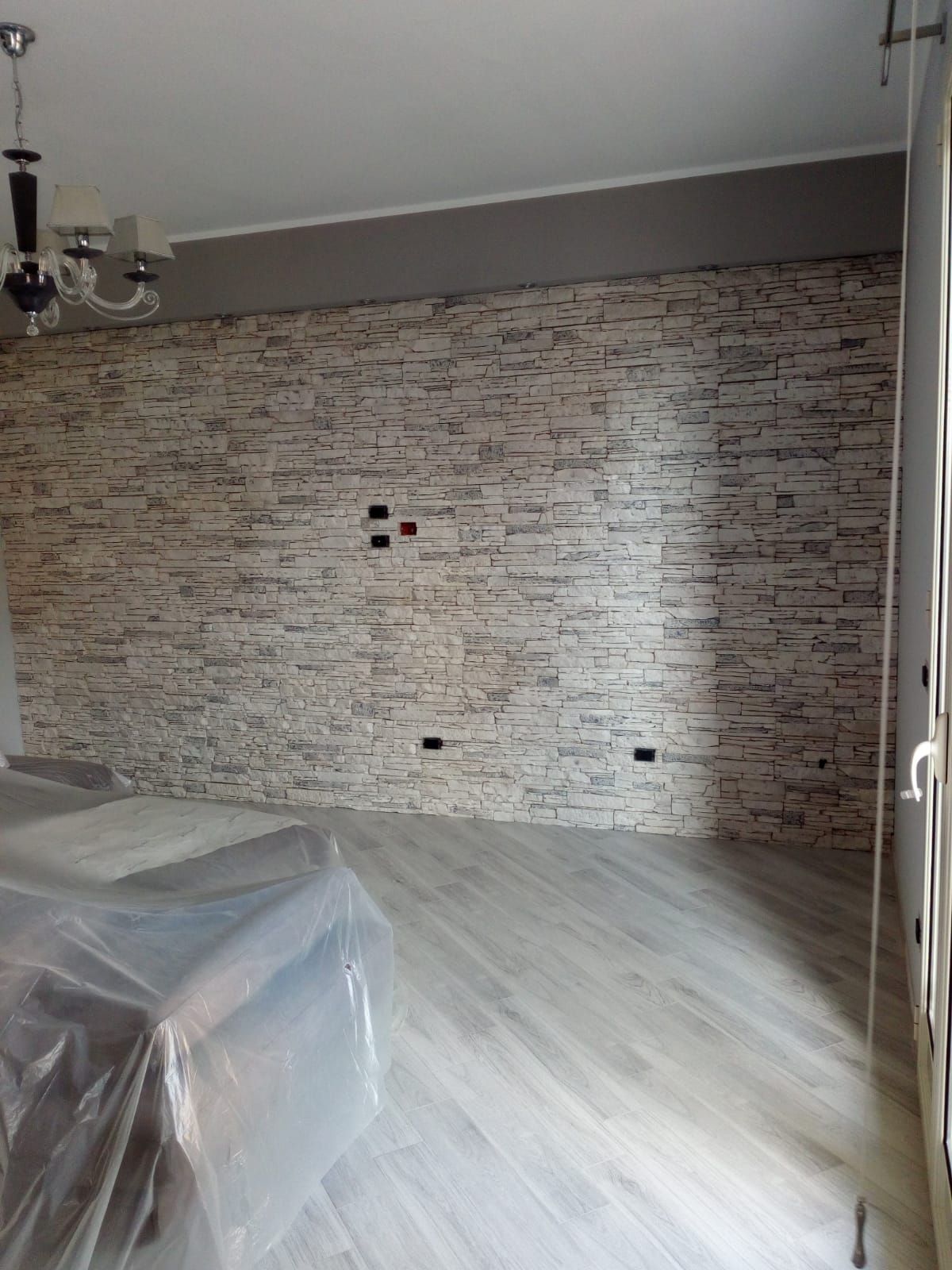 un soggiorno con un muro di pietra e un pavimento in legno