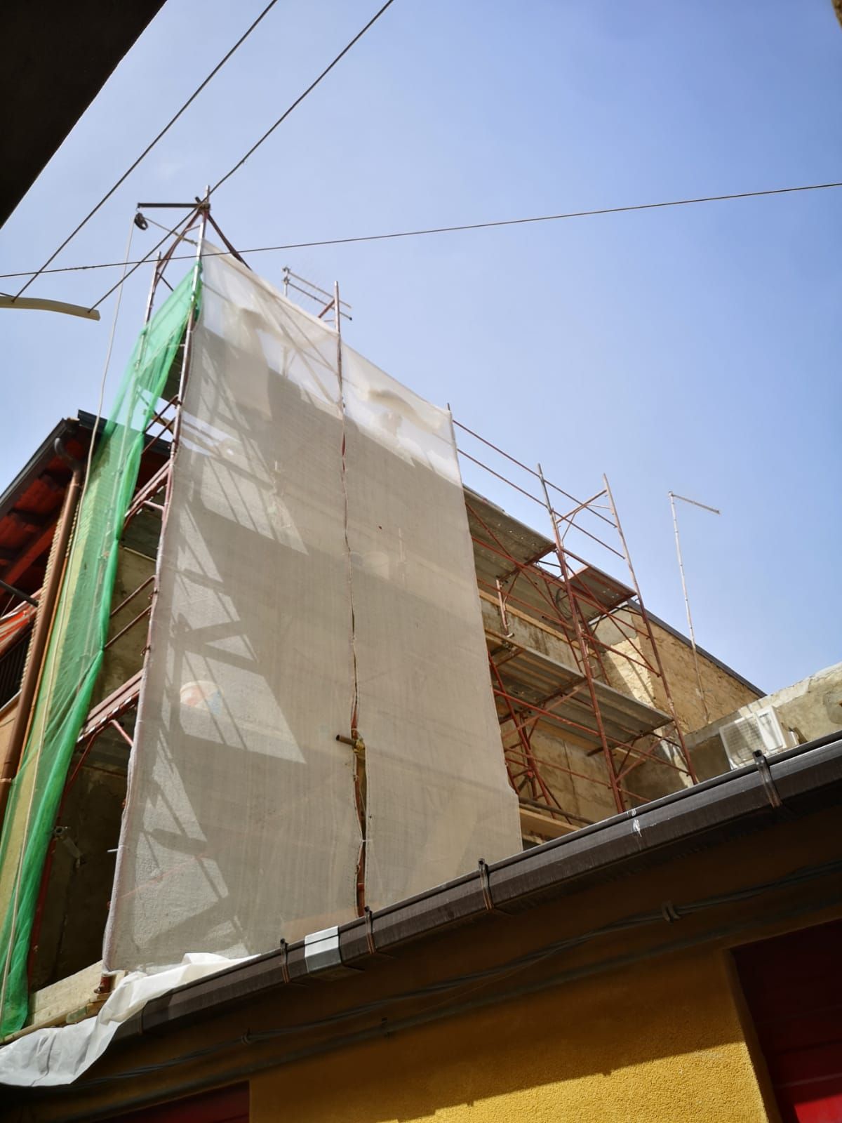 un edificio giallo è coperto di impalcature e un telo bianco