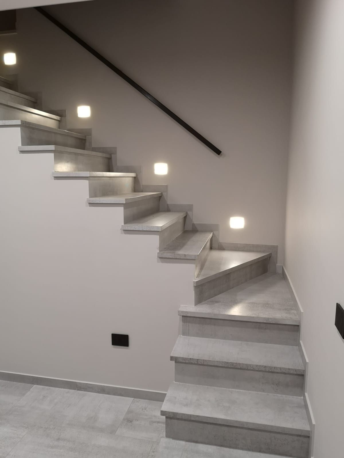 una scala con gradini bianchi e un corrimano nero