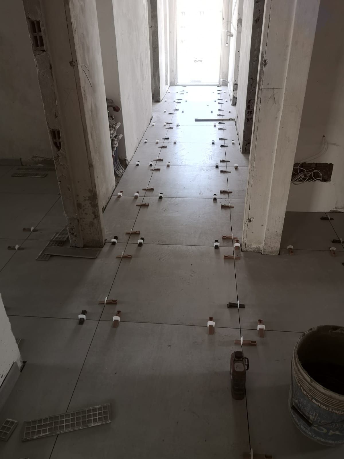 un secchio di cemento è seduto sul pavimento di un corridoio in costruzione