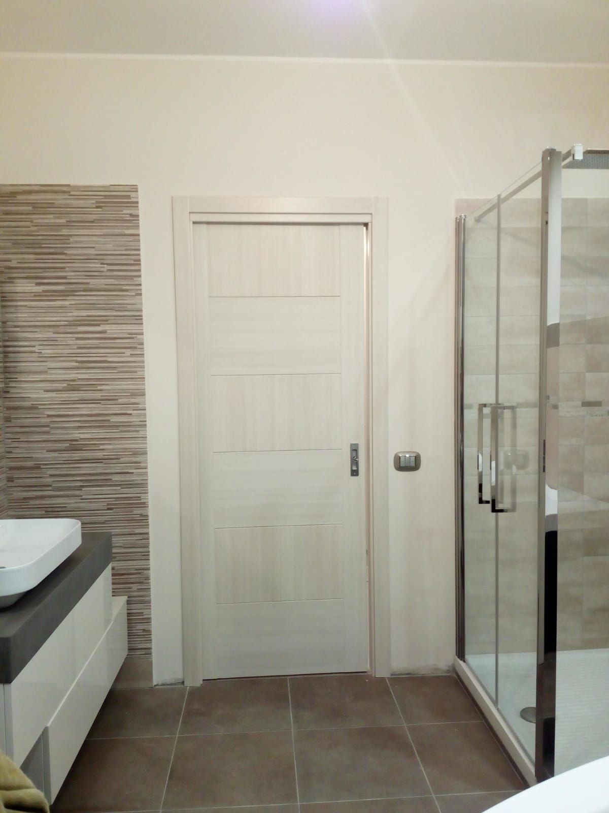 un bagno con lavabo e doccia e una porta bianca