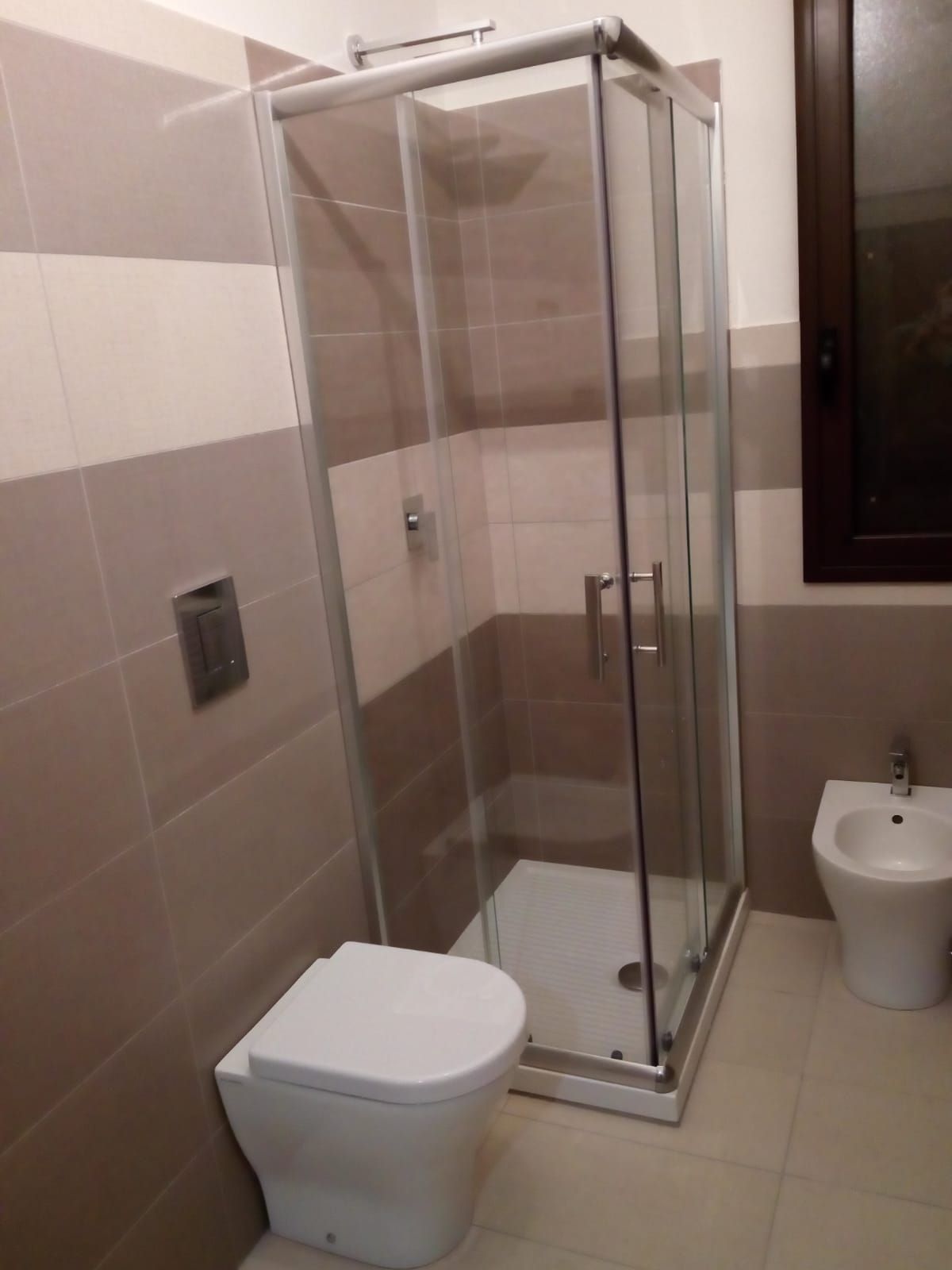 un bagno con un wc e un bidet e una cabina doccia