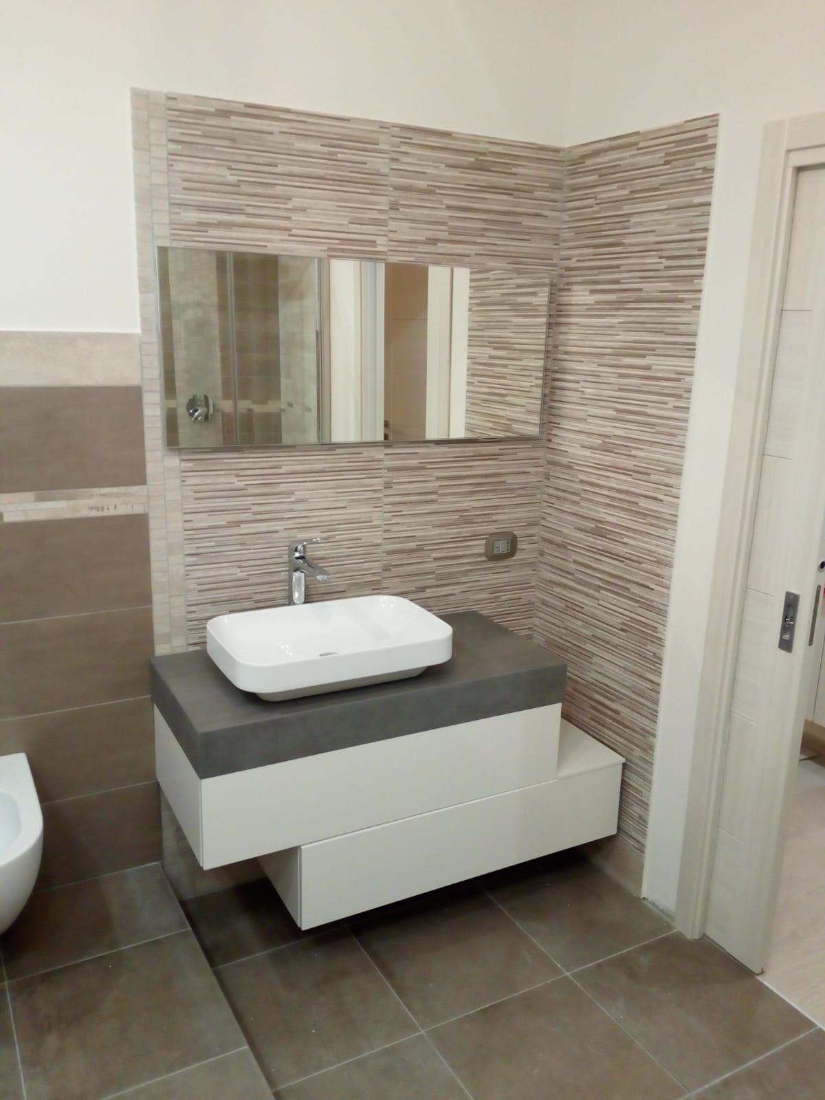 lavabo e specchio in un bagno con piastrelle marroni e bianche