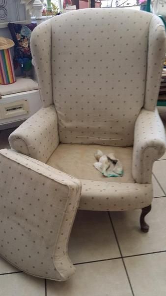 Beige upholstered armchair with a detached matching seat cushion in a tiled room