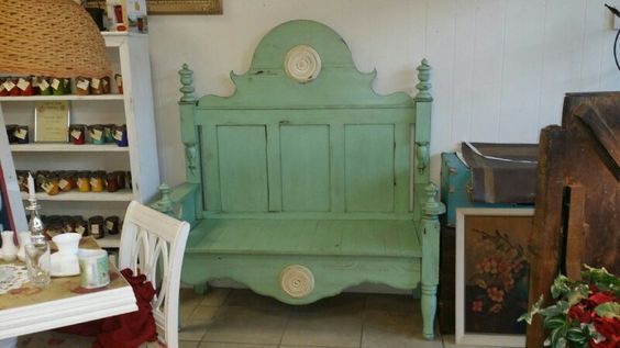 Mint-green antique bench in a shop display, surrounded by rustic furniture and decor.