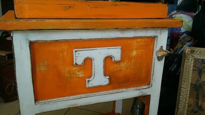White-framed orange cart or cabinet with a large white letter “T” on the front.