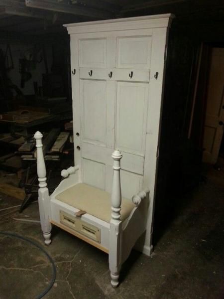 White wooden wardrobe with hooks and a small bench in a workshop or storage area