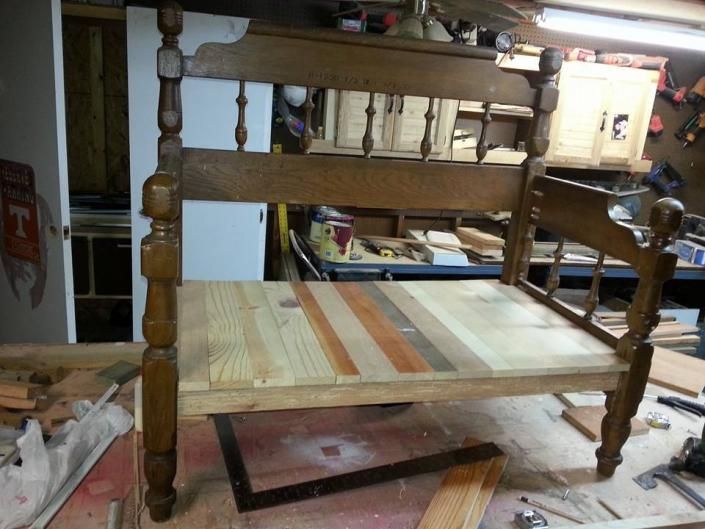Wooden chair frame with woven seat in a workshop, unfinished and resting on a stand.