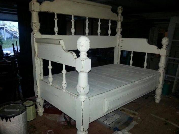 White wooden daybed or porch swing with spindled posts in a dim room