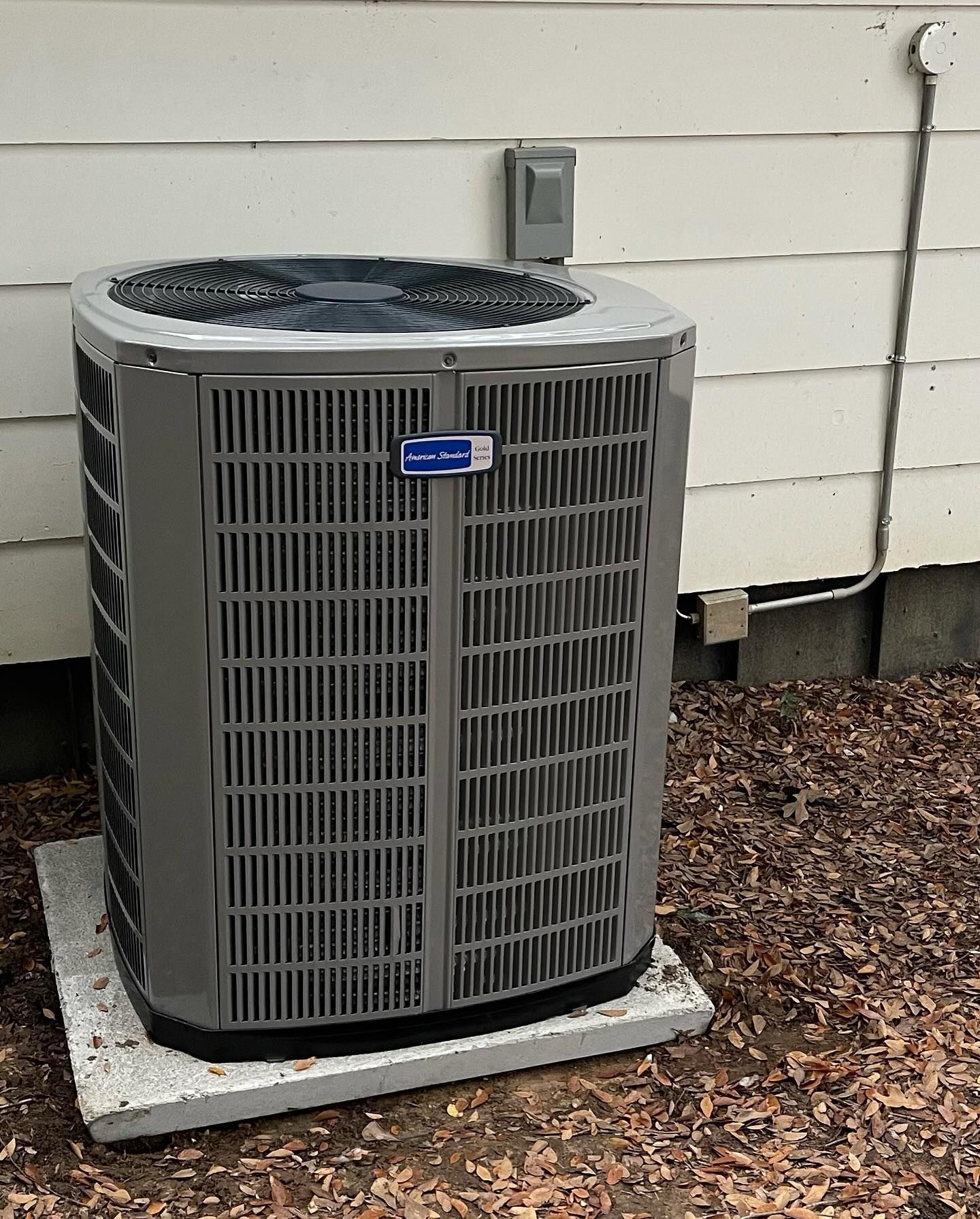 A large air conditioner is sitting outside of a house.