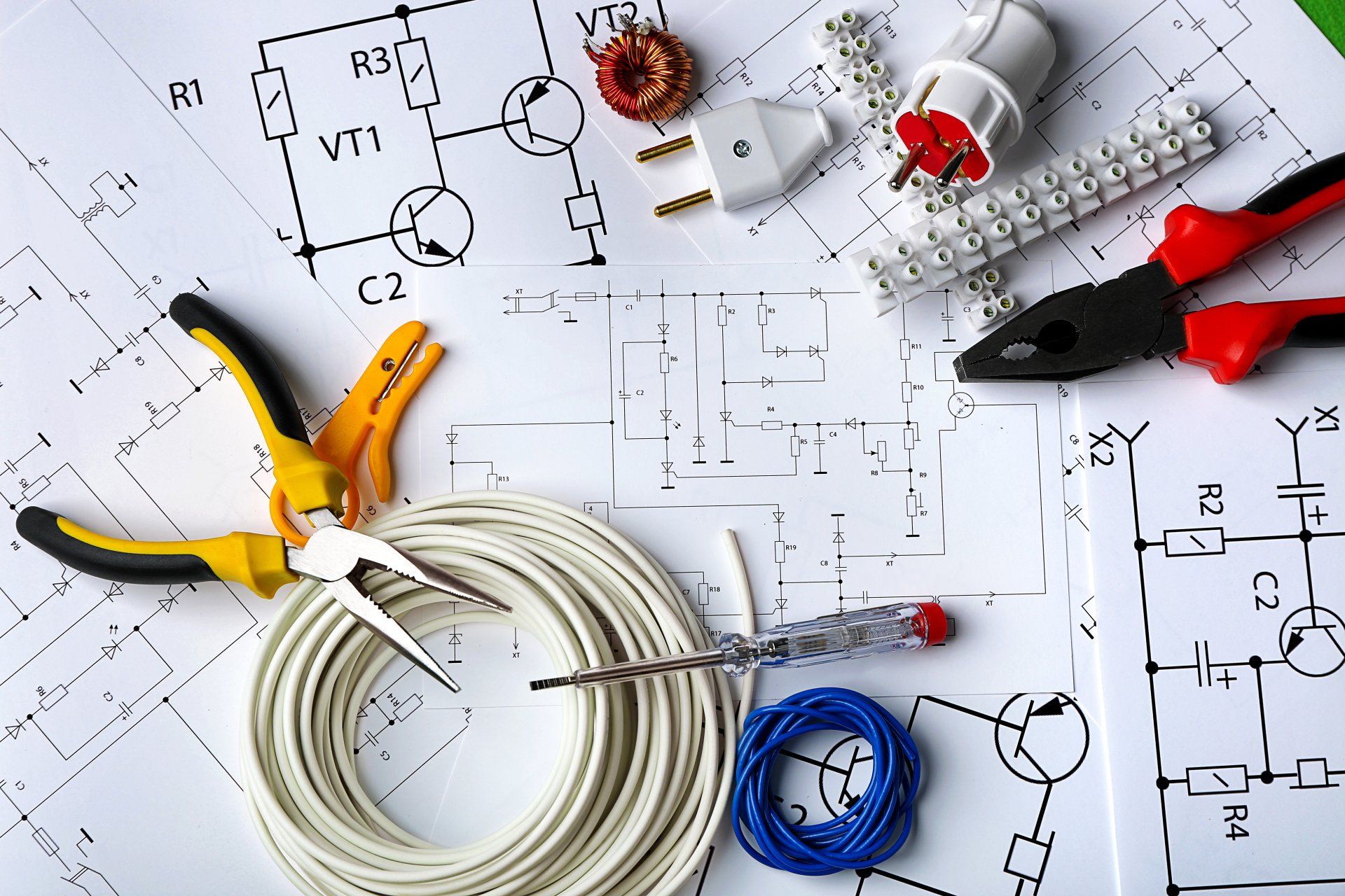 An electrician 's tools are laid out on top of a drawing