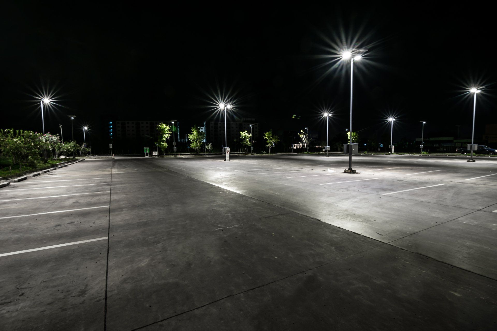 An empty parking lot at night with lots of lights on.