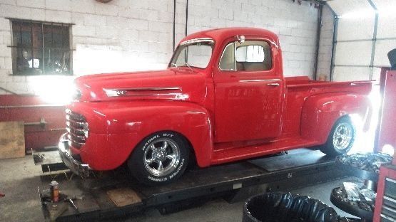 A red truck is sitting on a lift in a garage