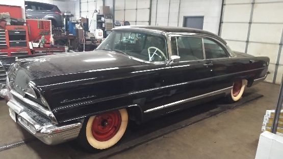 A black car with white tires is parked in a garage.