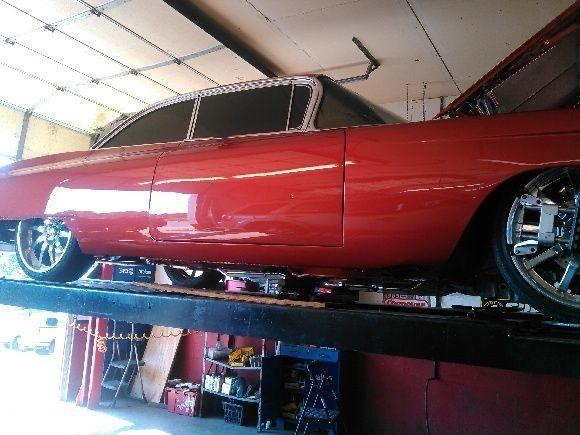 A red car is sitting on a lift in a garage