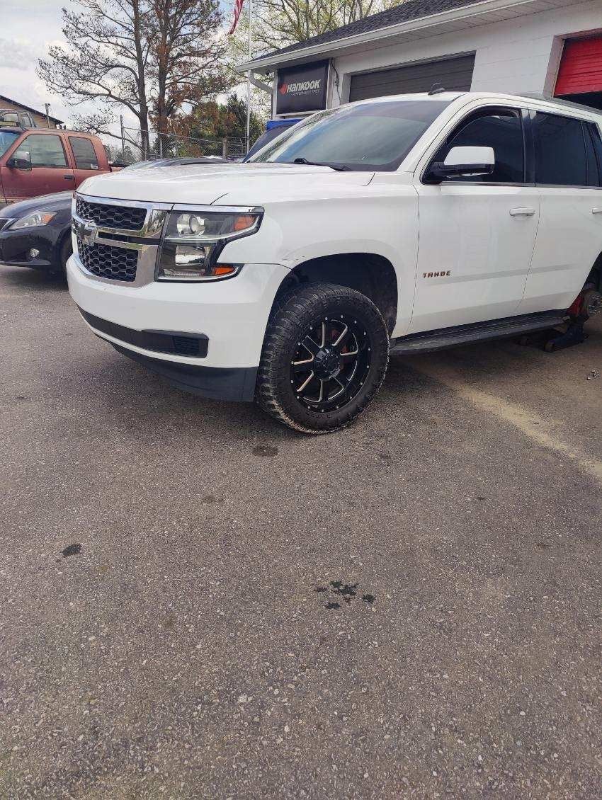 A white suv is parked in a parking lot in front of a building.