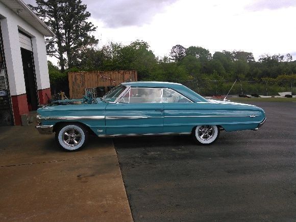 A blue car is parked in front of a garage