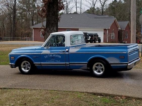 A blue truck is parked on the side of the road in front of a house.