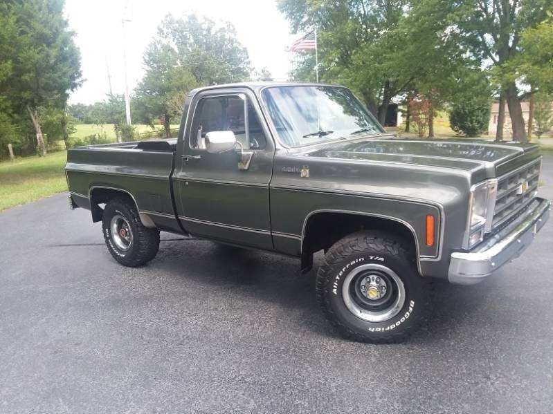 A green pickup truck is parked on the side of the road.