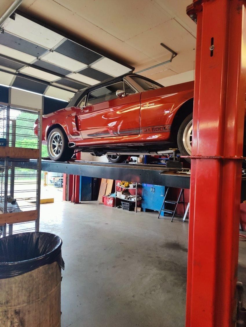 A red car is sitting on top of a red lift in a garage.