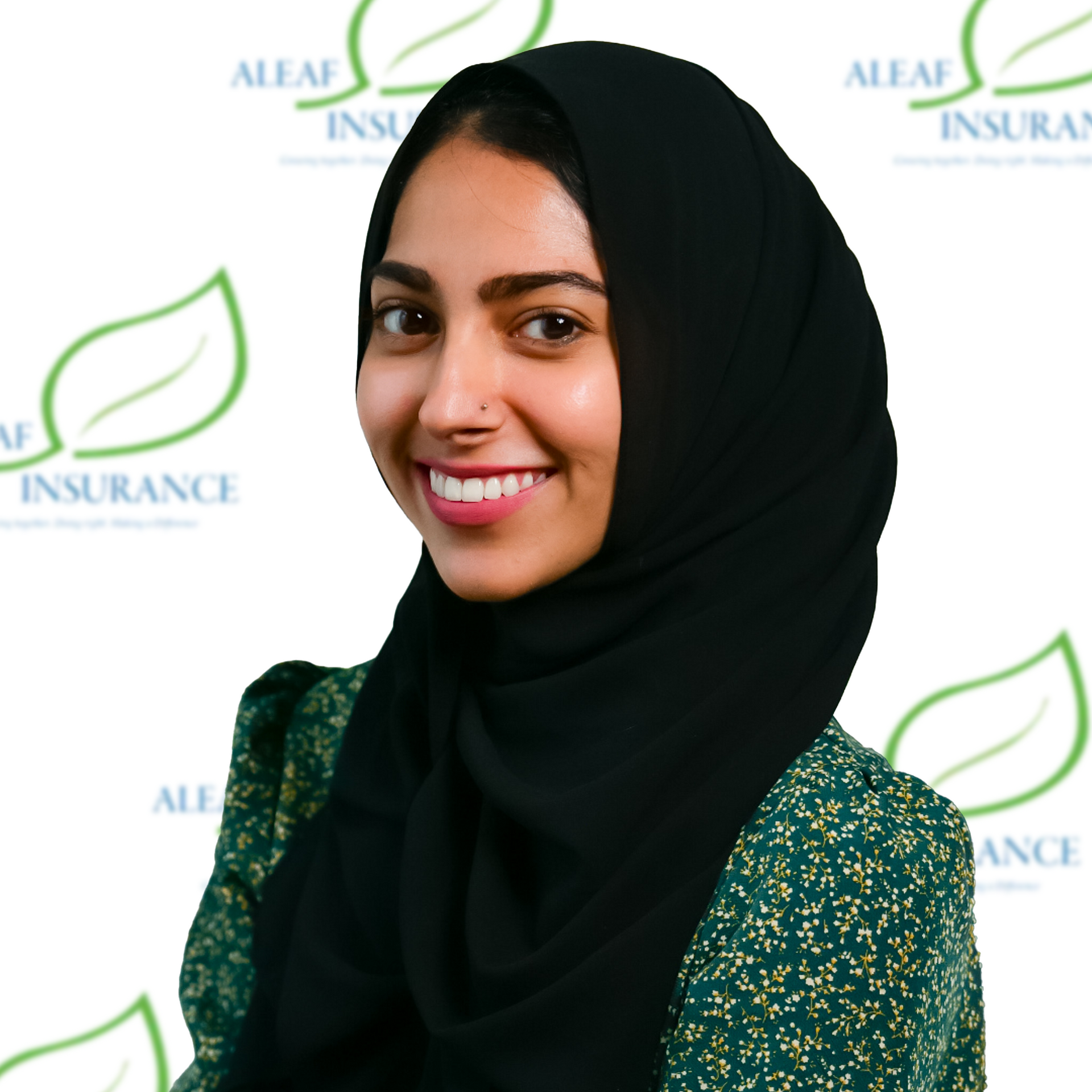 Smiling woman wearing a black hijab and floral top, in front of a green and white logo.