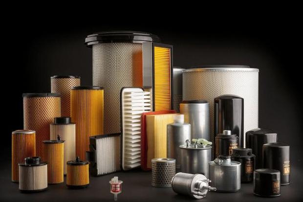 Raccolta di vari filtri dell'aria e del carburante di diverse forme e dimensioni su sfondo nero.